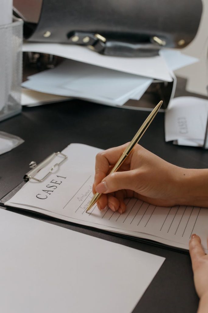 Close-up of a persons hand writing on a case document with a gold pen, emphasizing professionalism.